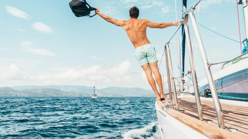 Man enjoying freedom by jumping into the ocean from a sailboat in Greece.