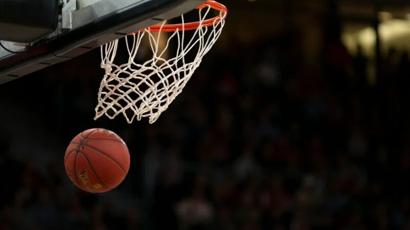 A basketball going through the hoop during a fast-paced game, capturing the excitement of the sport.