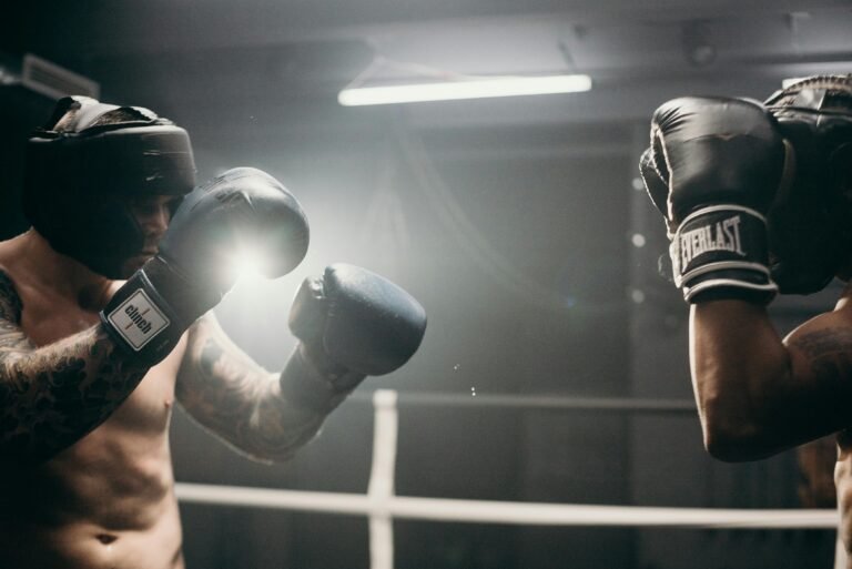 Two men sparring in a dimly lit gym, showcasing intense boxing training and athleticism.
