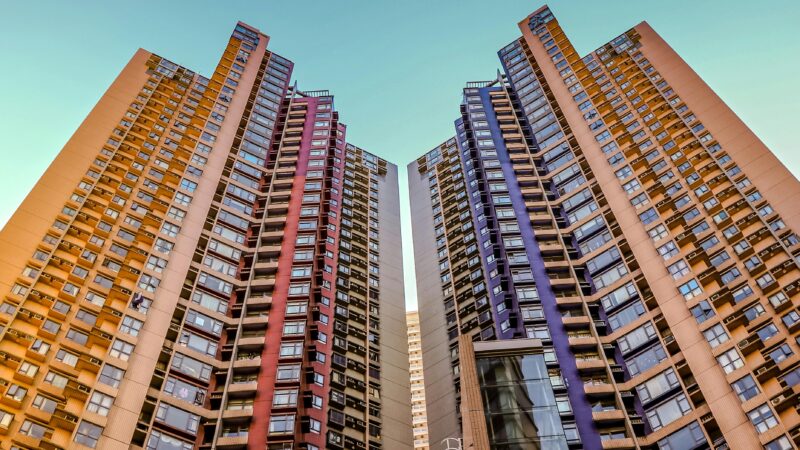 Tall, colorful skyscrapers reaching into the blue sky in Hong Kong, showcasing modern architecture.