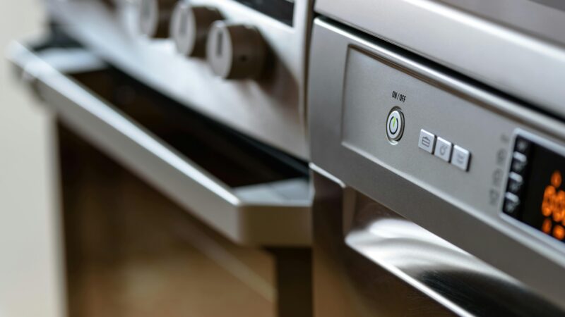 Close-up view of modern stainless steel kitchen appliances with focus on dishwasher and oven.